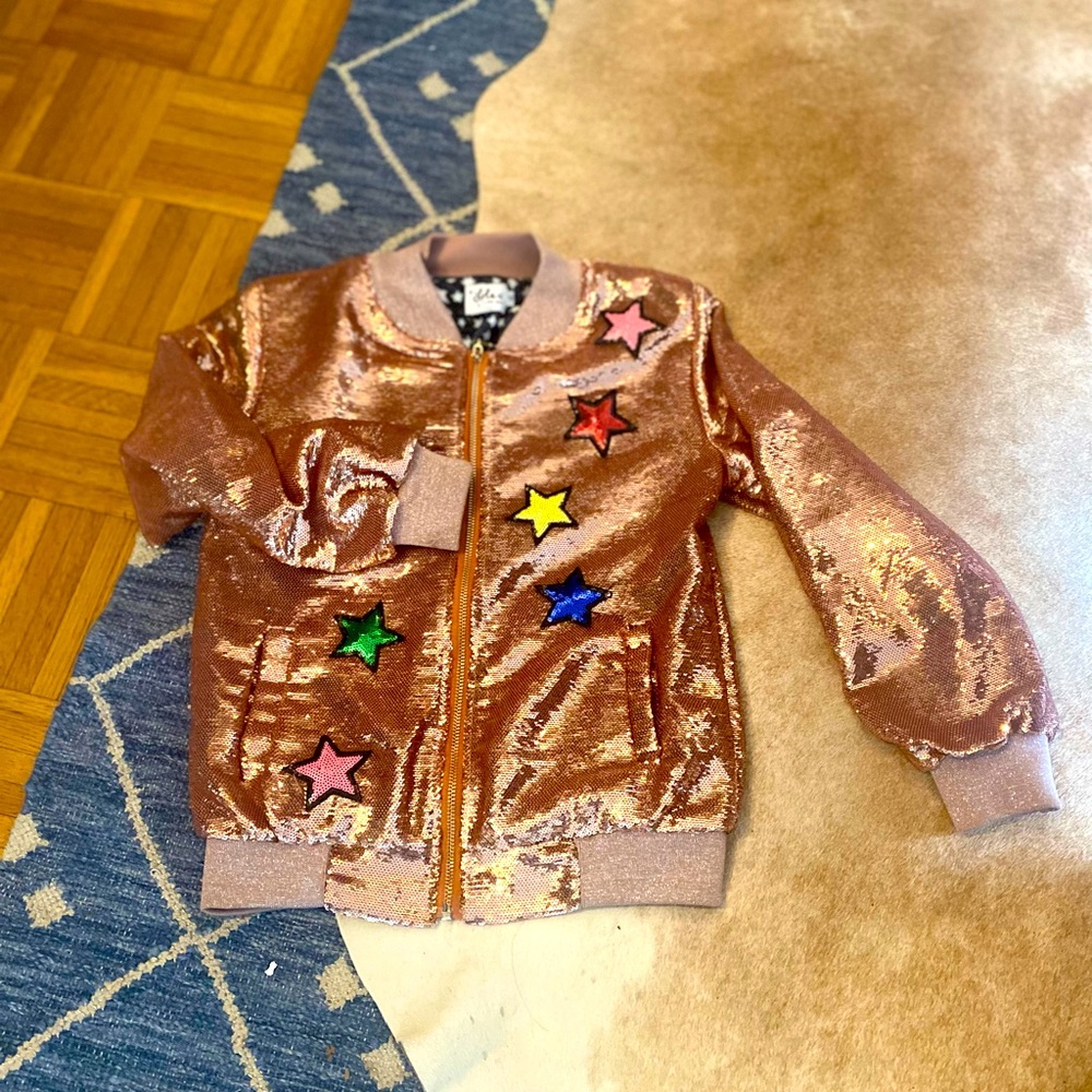 A Lola+the boys jacket with a unicorn on the back and stars on the front.
